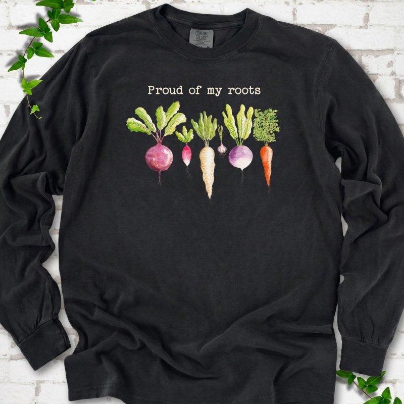 Black Comfort Colors® long sleeve T-shirt shown flat with "Proud of My Roots" text above watercolor-style root vegetables