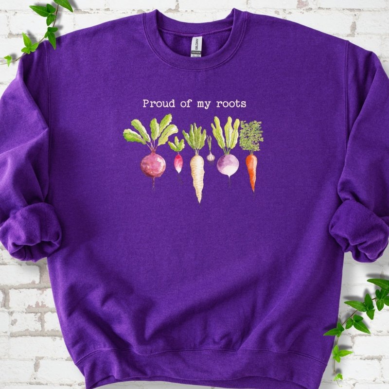 Purple classic sweatshirt shown flat with "Proud of My Roots" text above watercolor-style root vegetables