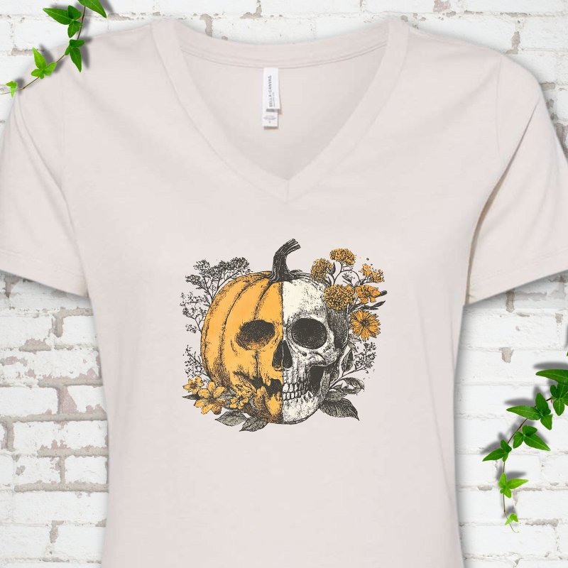 Heather Dust Bella Canvas® ladies' V-neck T-shirt flat lay featuring a half-pumpkin, half-skull botanical Halloween graphic.