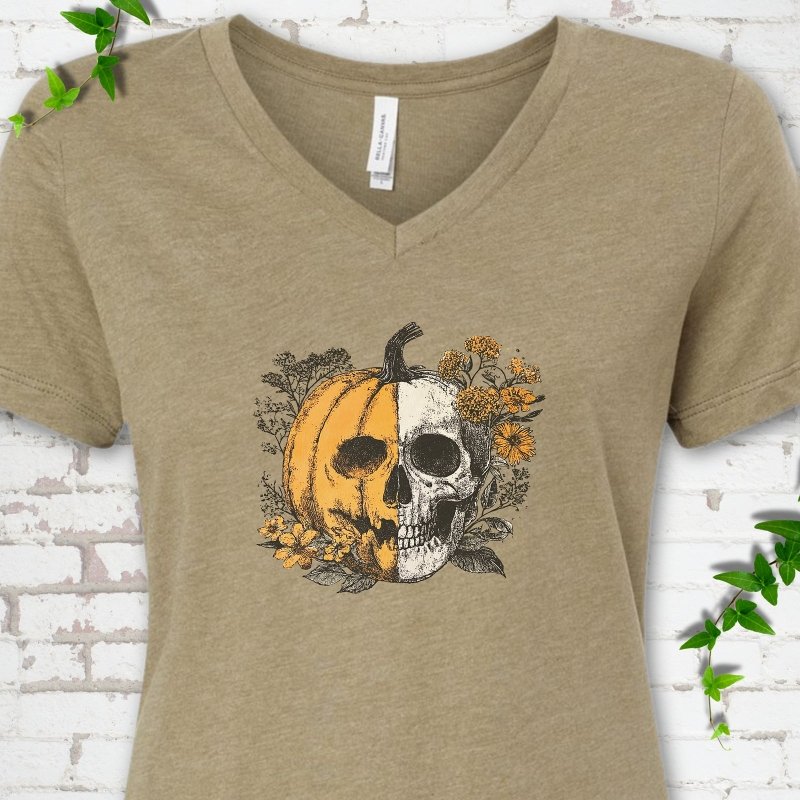 Heather Olive Bella Canvas® ladies' V-neck T-shirt flat lay featuring a half-pumpkin, half-skull botanical Halloween graphic.