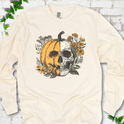 Ivory Comfort Colors® long sleeve T-shirt flat lay featuring a half-pumpkin, half-skull botanical Halloween graphic.