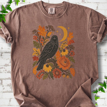 Espresso T-shirt flat lay with a black raven, crescent moon and warm autumn flowers and foliage.