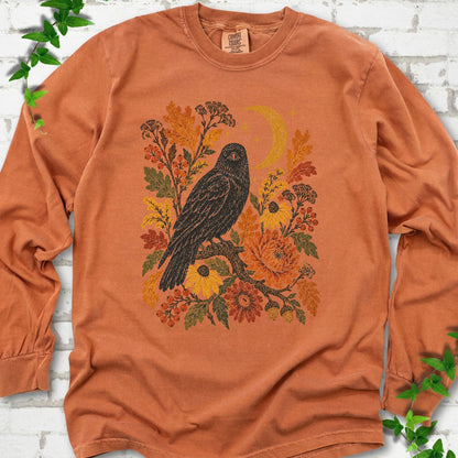 Yam long sleeve T-shirt flat lay with a black raven, crescent moon and warm autumn flowers and foliage.