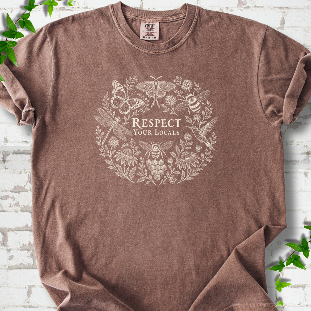 Espresso Comfort Colors® T-shirt flat lay featuring the words “Respect Your Locals” surrounded by pollinating insects, a hummingbird and flowers.