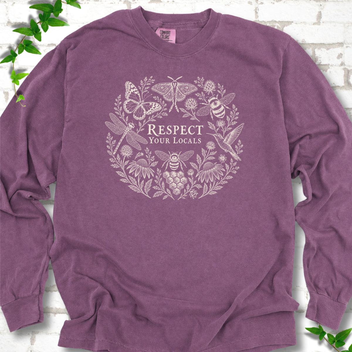Berry Comfort Colors® long sleeve tee flat lay featuring the words “Respect Your Locals” surrounded by pollinating insects, a hummingbird and flowers.