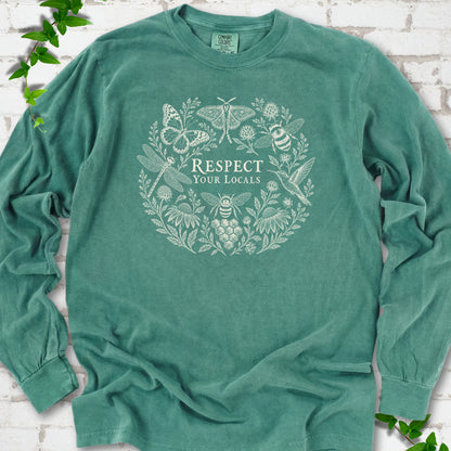 Light Green Comfort Colors® long sleeve tee flat lay featuring the words “Respect Your Locals” surrounded by pollinating insects, a hummingbird and flowers.