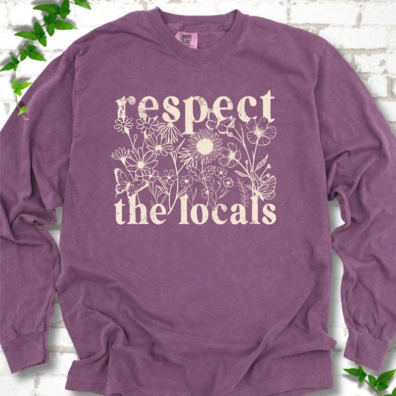 Berry Comfort Colors® long sleeve T-shirt flat lay featuring the words Respect the Locals with native wildflowers and pollinators.