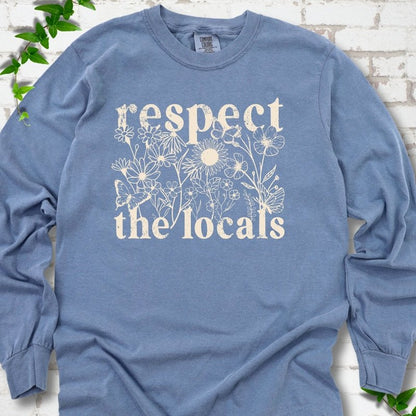 Blue Jean Comfort Colors® long sleeve T-shirt flat lay featuring the words Respect the Locals with native wildflowers and pollinators.