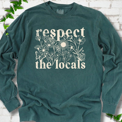 Blue Spruce Comfort Colors® long sleeve T-shirt flat lay featuring the words Respect the Locals with native wildflowers and pollinators.