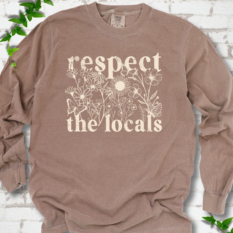 Espresso Comfort Colors® long sleeve T-shirt flat lay featuring the words Respect the Locals with native wildflowers and pollinators.