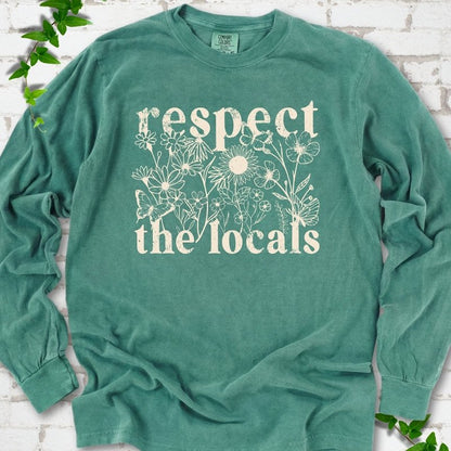 Light Green Comfort Colors® long sleeve T-shirt flat lay featuring the words Respect the Locals with native wildflowers and pollinators.