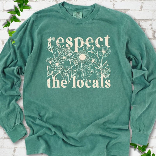 Light Green Comfort Colors® long sleeve T-shirt flat lay featuring the words Respect the Locals with native wildflowers and pollinators.