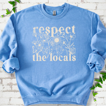 Carolina Blue Gildan® 18000 crewneck sweatshirt flat lay featuring the words “Respect the Locals” with wildflowers and butterflies.