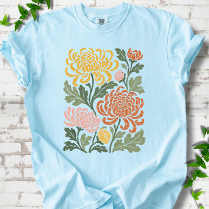 Chambray Comfort Colors® short sleeve T-shirt flat lay with a distressed multicolor chrysanthemum garden graphic on a white brick background with ivy accents