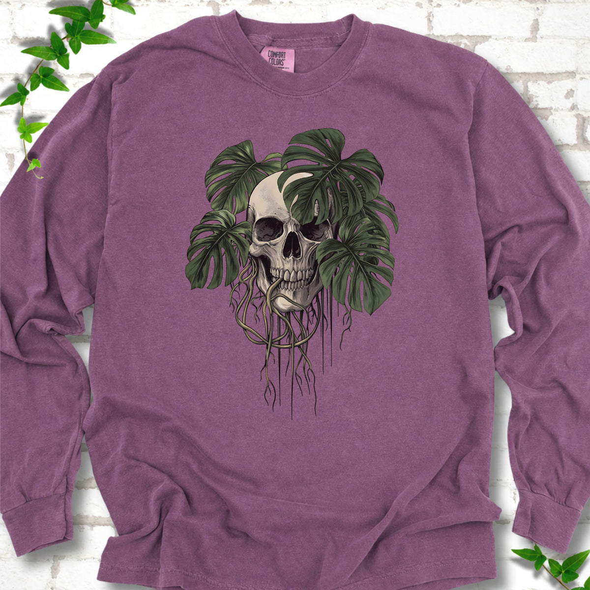 Berry Comfort Colors T-shirt shown flat with the Root Bound Monstera skull and trailing roots graphic