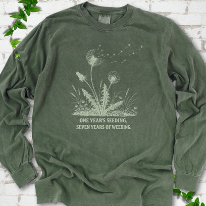 Hemp long sleeve T-shirt flat lay with dandelion seed heads, drifting seeds and 'One year's seeding, seven years of weeding' lettering.