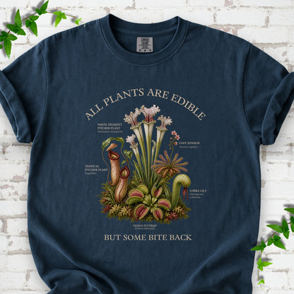 Midnight Comfort Colors® T-shirt front mockup featuring a botanical illustration of various carnivorous plants including a Venus Flytrap, Pitcher Plants, Cape Sundew, and Cobra Lily.