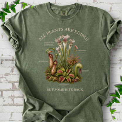 Moss Comfort Colors® T-shirt front mockup featuring a botanical illustration of various carnivorous plants including a Venus Flytrap, Pitcher Plants, Cape Sundew, and Cobra Lily.