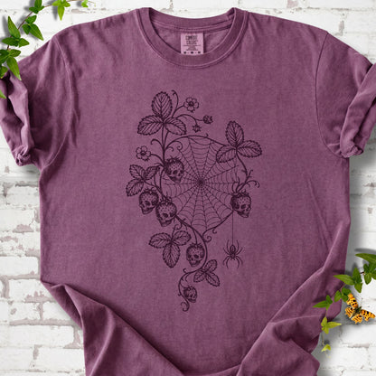 Berry Comfort Colors® T-shirt flat lay featuring skull-shaped strawberries, curling leaves, a spiderweb and a hanging spider.
