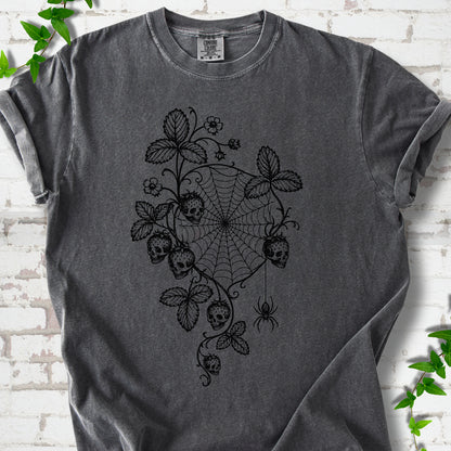 Pepper Comfort Colors® T-shirt flat lay featuring skull-shaped strawberries, curling leaves, a spiderweb and a hanging spider.