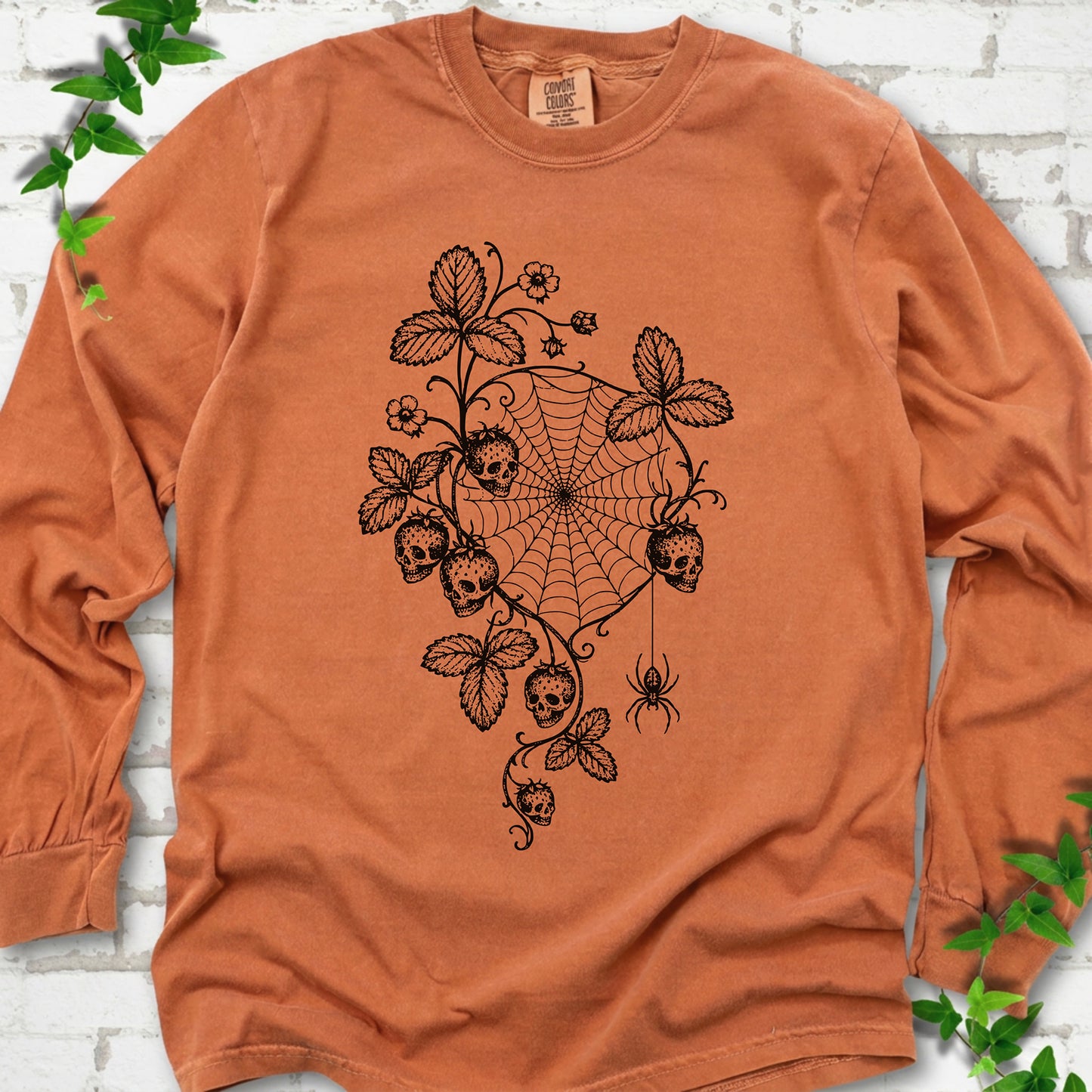 Yam Comfort Colors® long sleeve T-shirt flat lay featuring skull-shaped strawberries, curling leaves, a spiderweb and a hanging spider.