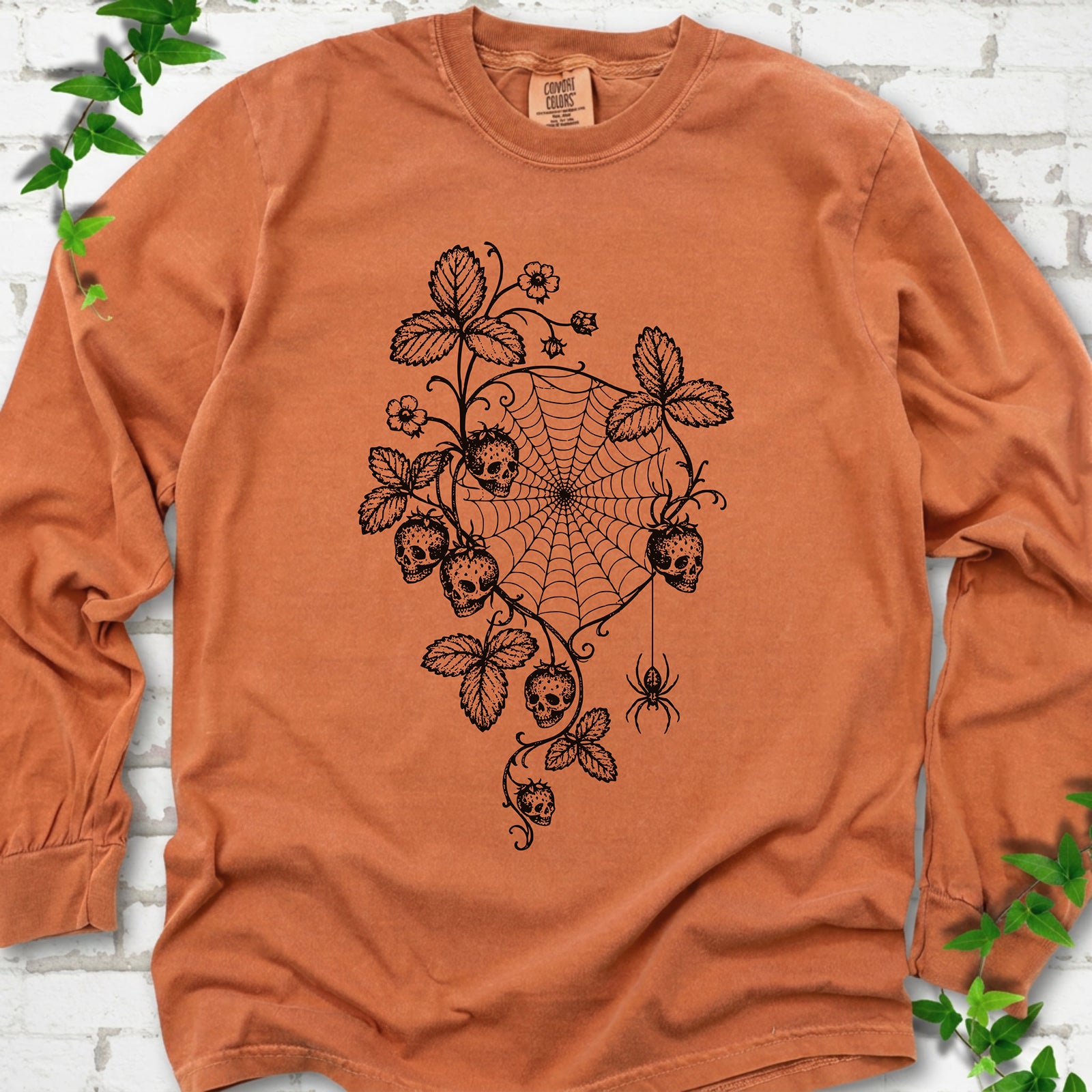 Yam Comfort Colors® long sleeve T-shirt flat lay featuring skull-shaped strawberries, curling leaves, a spiderweb and a hanging spider.