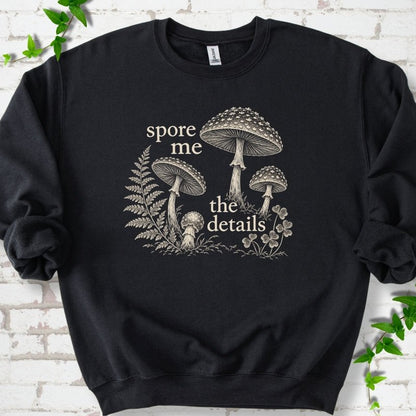 Black crewneck sweatshirt with "spore me the details" and engraved toadstools, fern and clover in cream ink