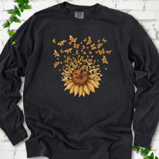 Black Comfort Colors® long sleeve T-shirt flat lay featuring a sunflower releasing a burst of orange butterflies.