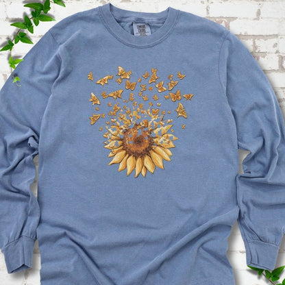 Blue Jean Comfort Colors® long sleeve T-shirt flat lay featuring a sunflower releasing a burst of orange butterflies.