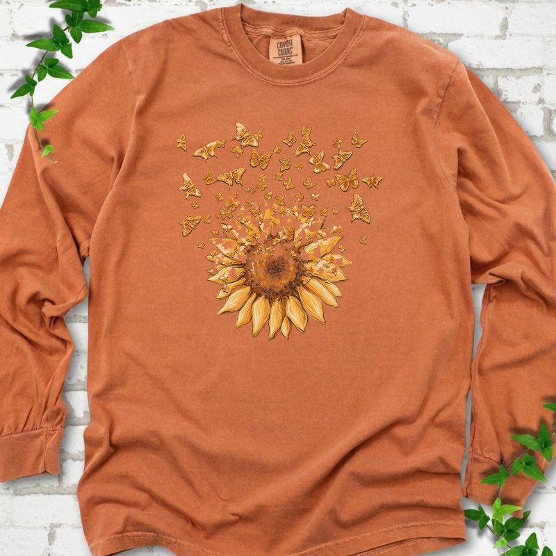 Yam Comfort Colors® long sleeve T-shirt flat lay featuring a sunflower releasing a burst of orange butterflies.