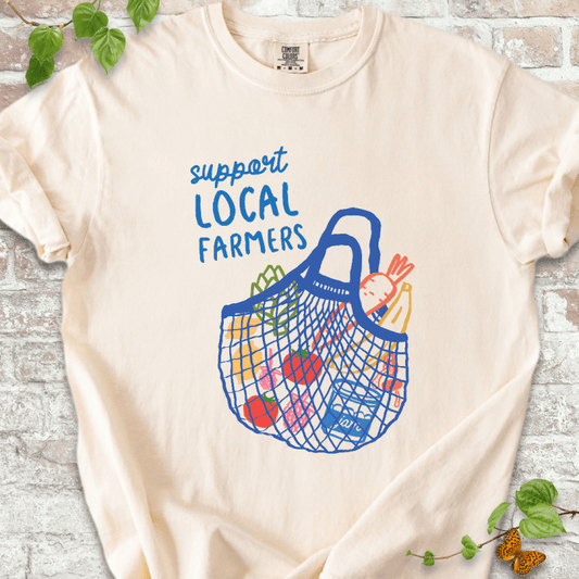Colorful Support Local Farmers T-shirt on Ivory Comfort Colors™ tee, featuring a hand-drawn string bag filled with fresh veggies and fruit.