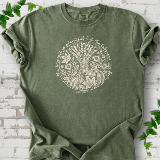 Moss T-shirt flat lay with cream wheat, pumpkins and leaves in a harvest circle, the Matthew 9:37 verse around it and its reference below.