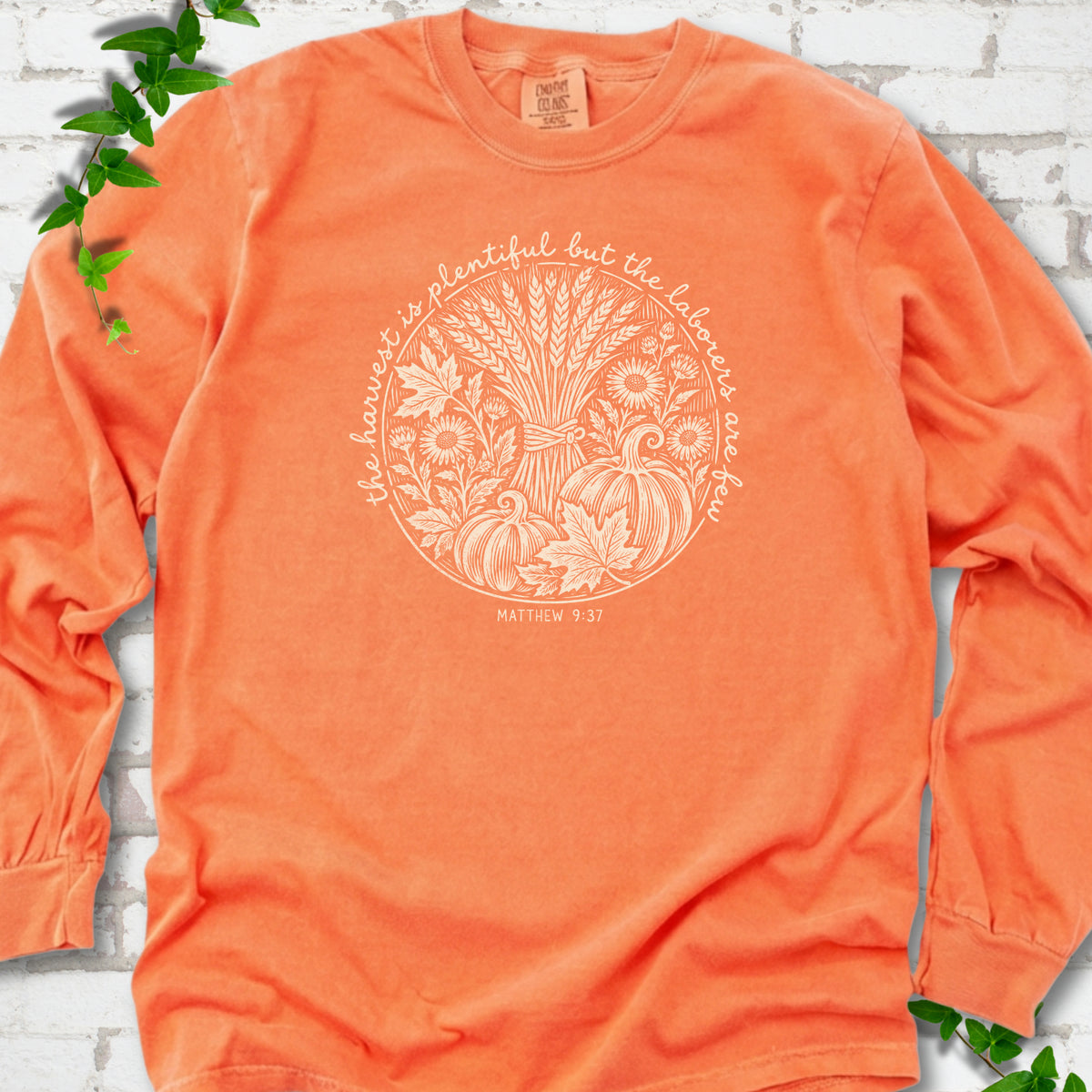Melon long sleeve T-shirt flat lay with cream wheat, pumpkins and leaves in a harvest circle, the Matthew 9:37 verse around it and its reference below.