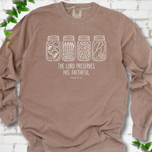 Espresso long sleeve T-shirt flat lay with white line-art illustrations of four mason jars filled with peaches, asparagus, blueberries and pickles above the words "The Lord Preserves His Faithful" and small "Psalm 31:23", on white brick with ivy sprigs.