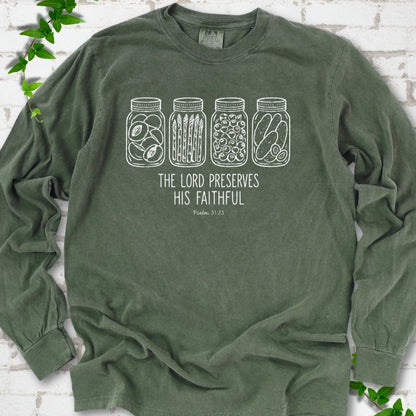 Hemp long sleeve T-shirt flat lay with white line-art illustrations of four mason jars filled with peaches, asparagus, blueberries and pickles above the words "The Lord Preserves His Faithful" and small "Psalm 31:23", on white brick with ivy sprigs.
