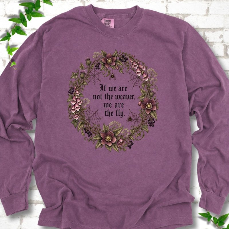 Berry long sleeve T-shirt flat-lay mockup with a gothic floral wreath, spider webs and "If we are not the weaver, we are the fly" lettering.