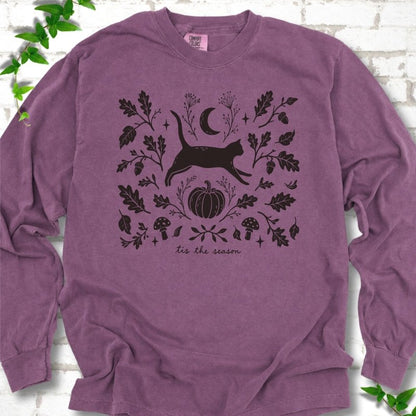Berry Comfort Colors® long sleeve T-shirt flat lay featuring a black cat leaping through autumn oak leaves, acorns, a moon, pumpkin and woodland mushrooms.