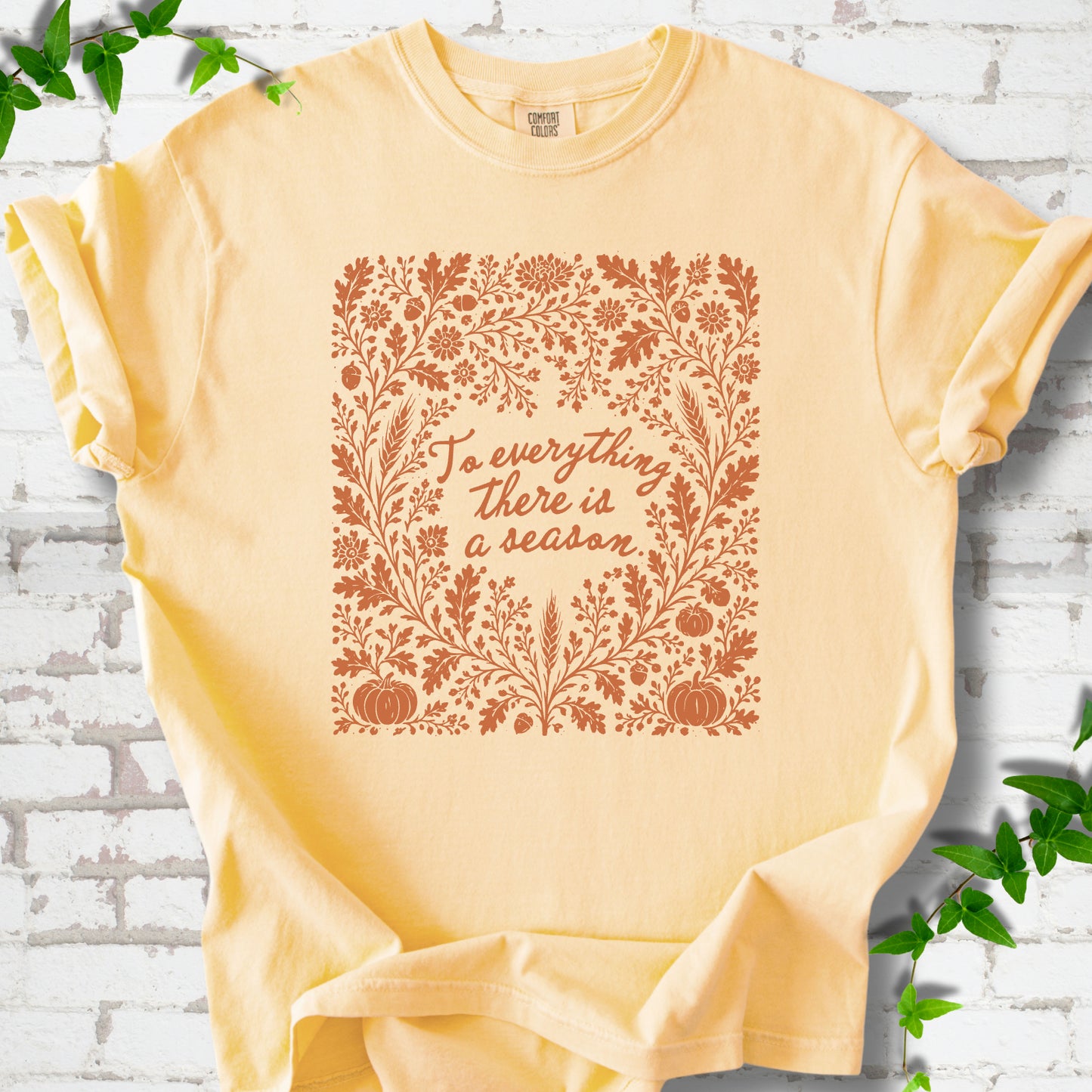 Butter Comfort Colors® T-shirt flat lay with botanical To Everything There Is a Season Bible verse artwork.