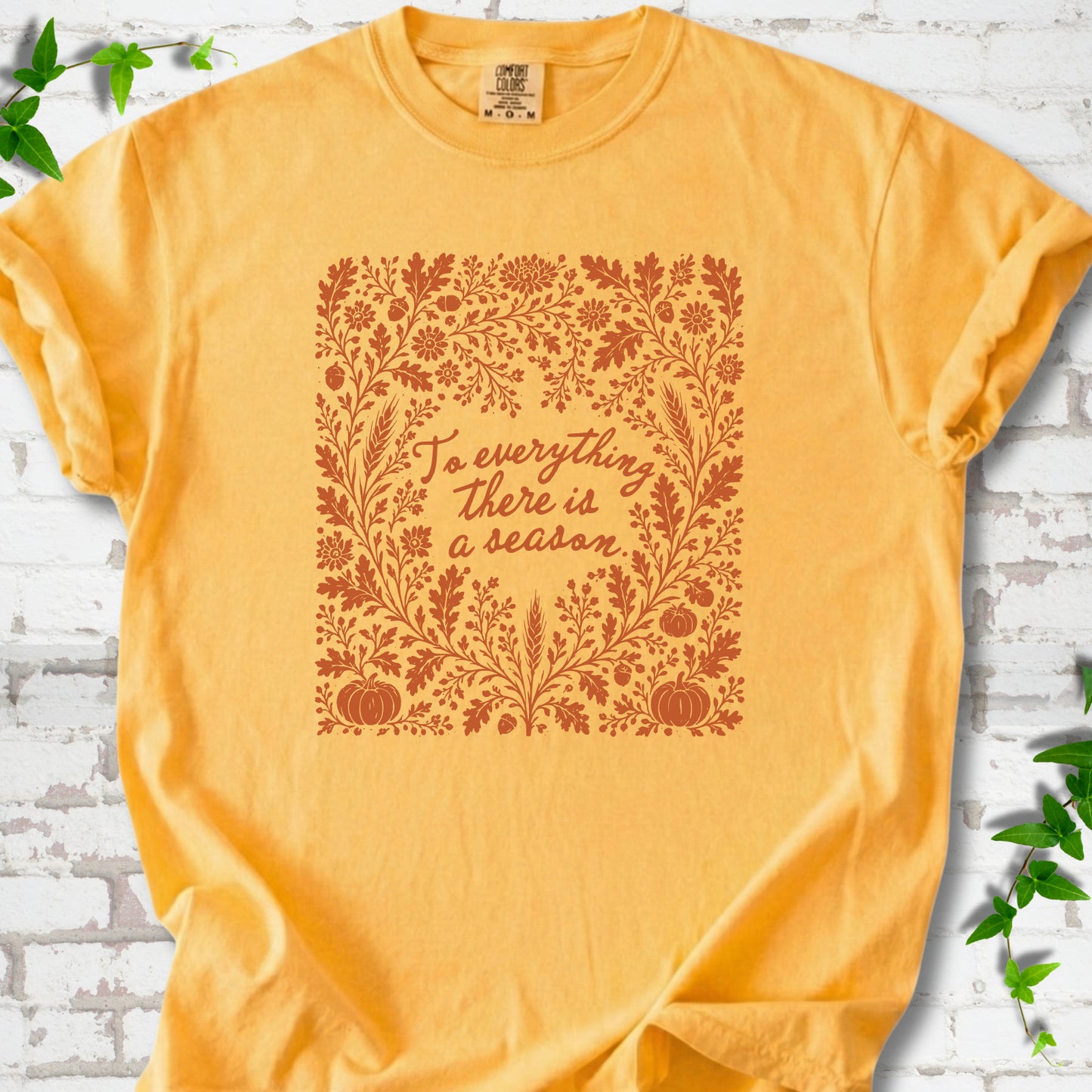 Citrus Comfort Colors® T-shirt flat lay with botanical To Everything There Is a Season Bible verse artwork.
