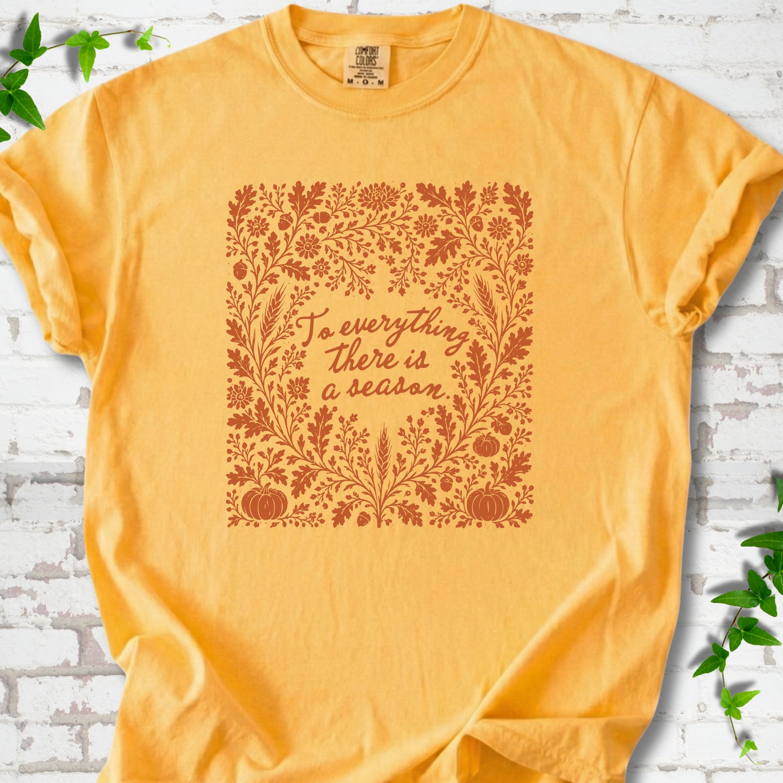 Citrus Comfort Colors® T-shirt flat lay with botanical To Everything There Is a Season Bible verse artwork.