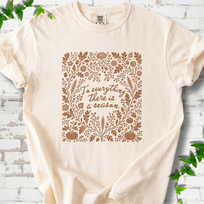Ivory Comfort Colors® T-shirt flat lay with botanical To Everything There Is a Season Bible verse artwork.