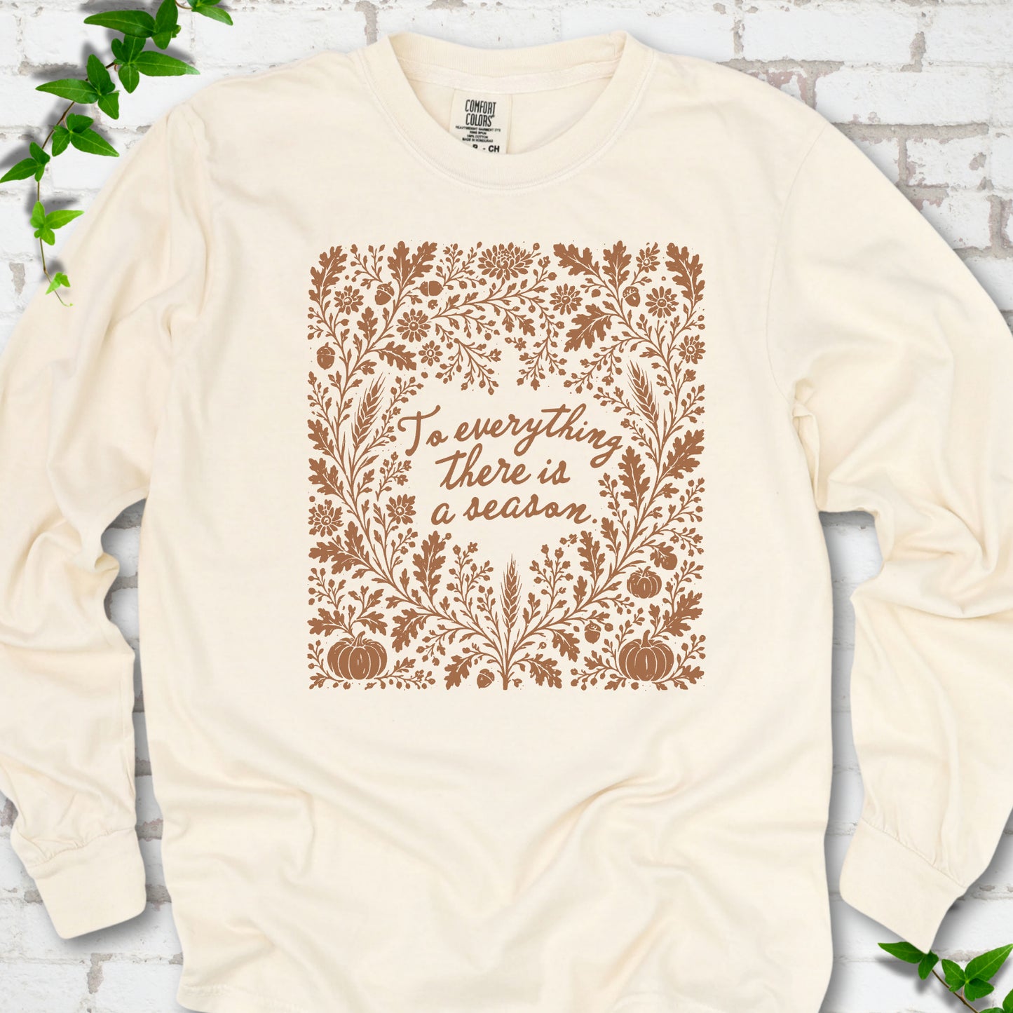 Ivory Comfort Colors® long sleeve T-shirt flat lay with botanical To Everything There Is a Season Bible verse artwork.