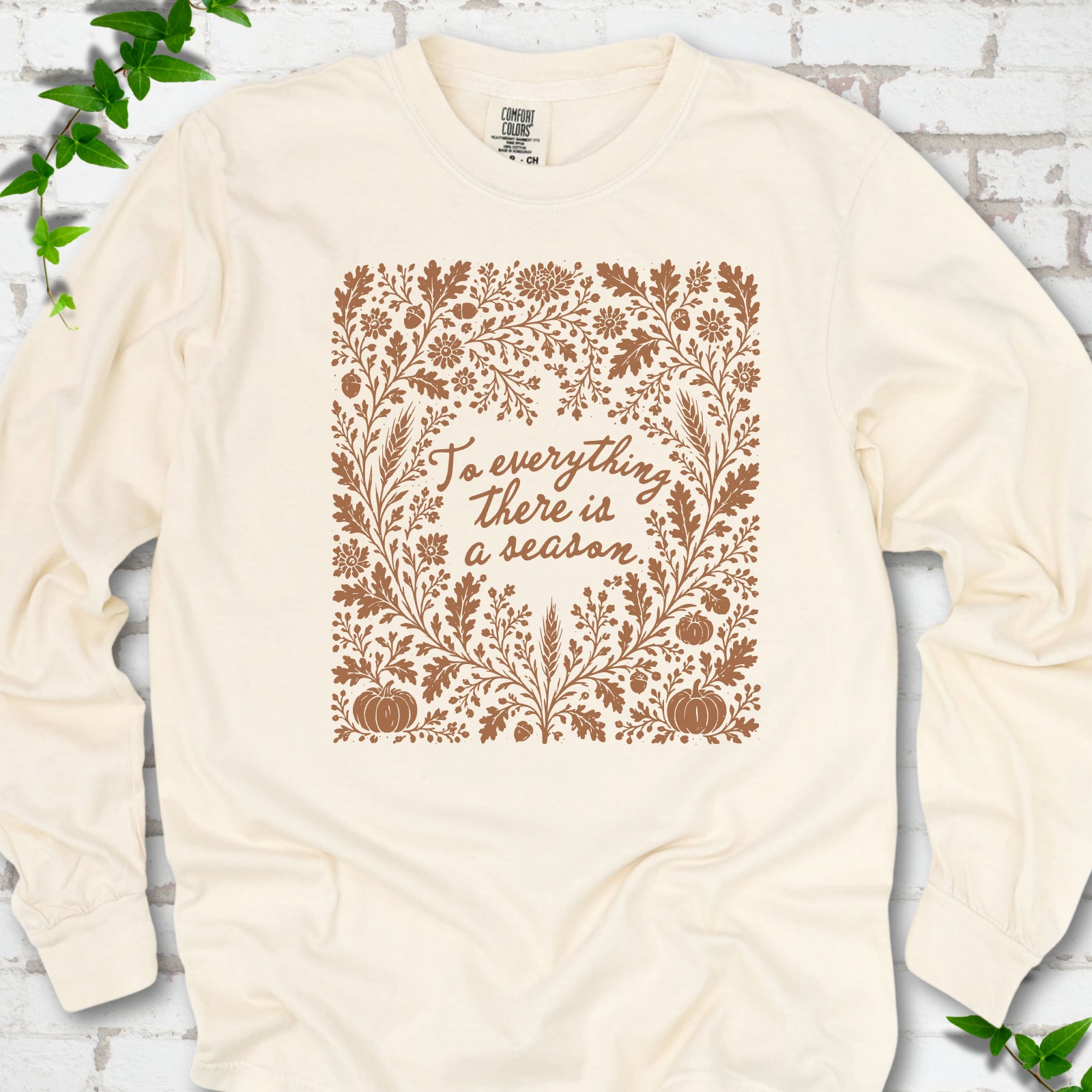 Ivory Comfort Colors® long sleeve T-shirt flat lay with botanical To Everything There Is a Season Bible verse artwork.