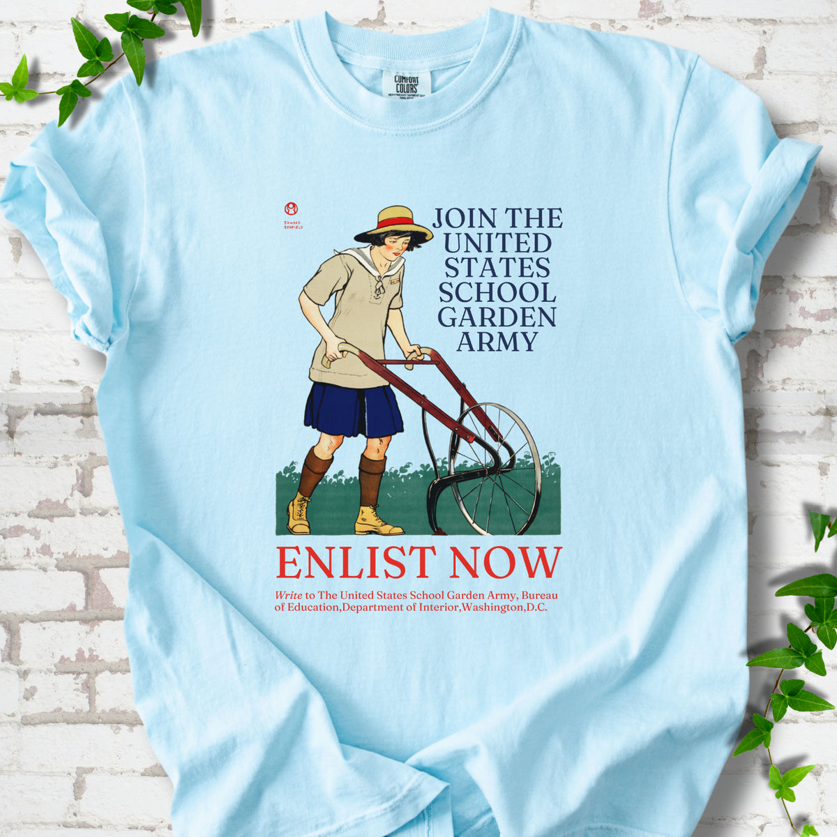 Chambray Comfort Colors® T-shirt featuring Edward Penfield’s 1918 School Garden Army poster with a young gardener, wheel hoe and “Enlist Now” text.
