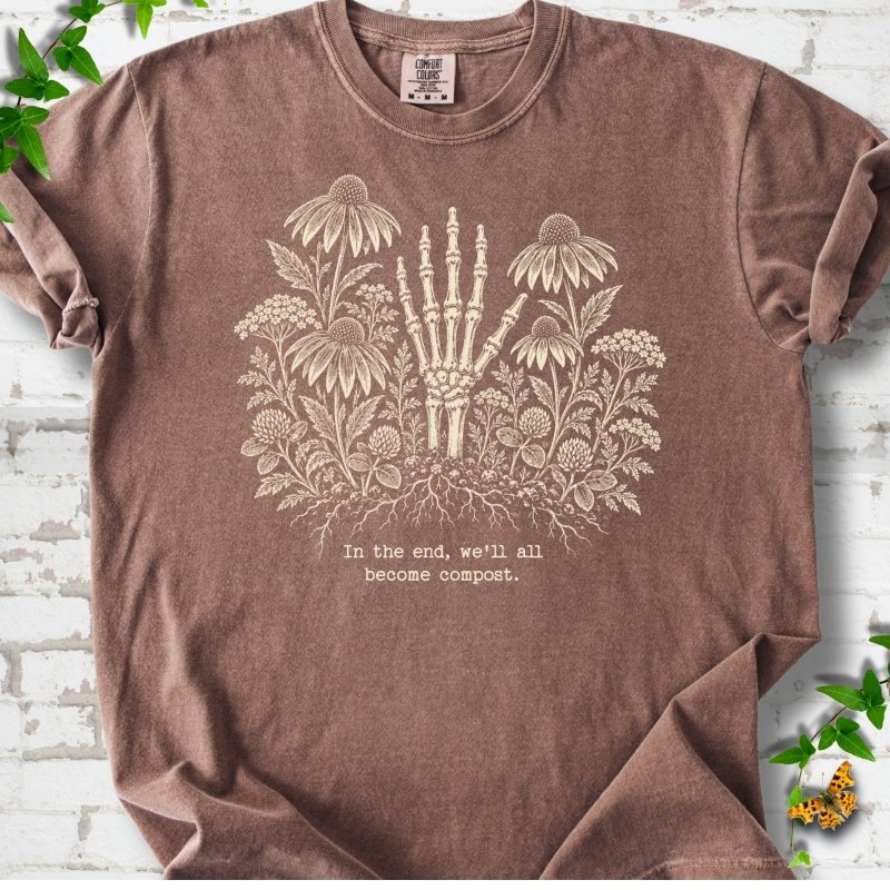 Espresso Comfort Colors® T-shirt featuring a cream botanical skeleton-hand graphic reading In the end, we'll all become compost