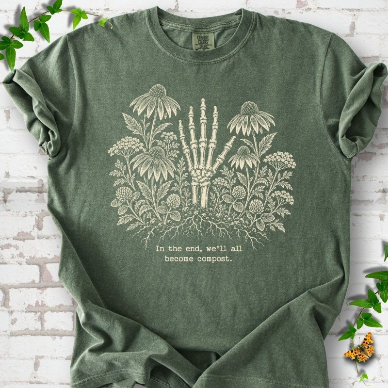 Moss Comfort Colors® T-shirt featuring a cream botanical skeleton-hand graphic reading In the end, we'll all become compost