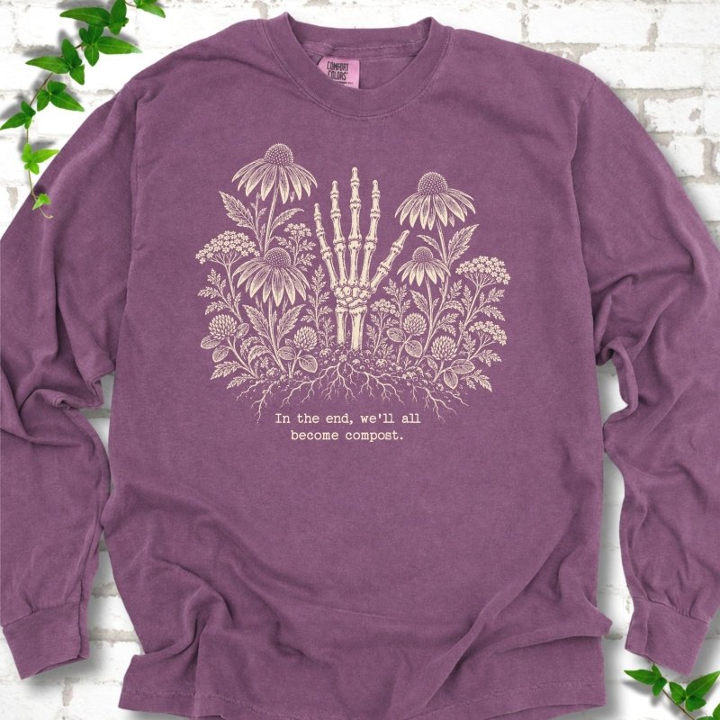Berry Comfort Colors® long sleeve T-shirt featuring a cream botanical skeleton-hand graphic reading In the end, we'll all become compost