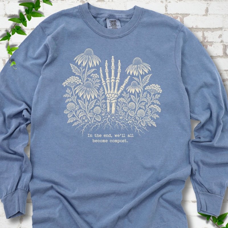 Blue Jean Comfort Colors® long sleeve T-shirt featuring a cream botanical skeleton-hand graphic reading In the end, we'll all become compost