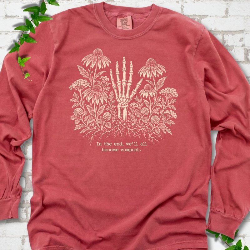 Crimson Comfort Colors® long sleeve T-shirt featuring a cream botanical skeleton-hand graphic reading In the end, we'll all become compost