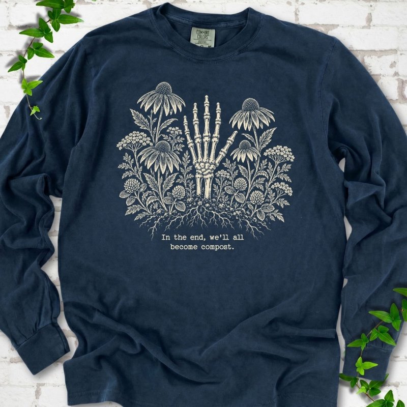 Midnight Comfort Colors® long sleeve T-shirt featuring a cream botanical skeleton-hand graphic reading In the end, we'll all become compost